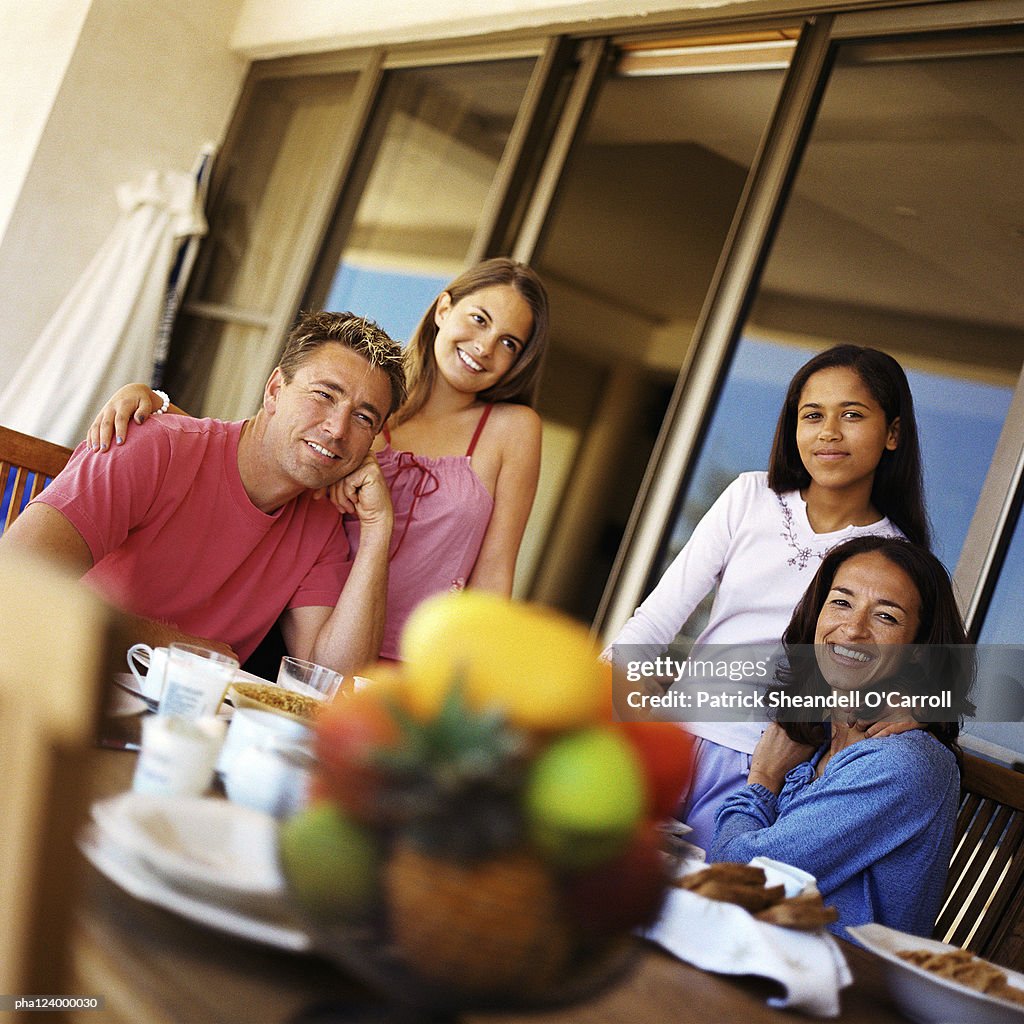 Couple and daughters at table, smiling