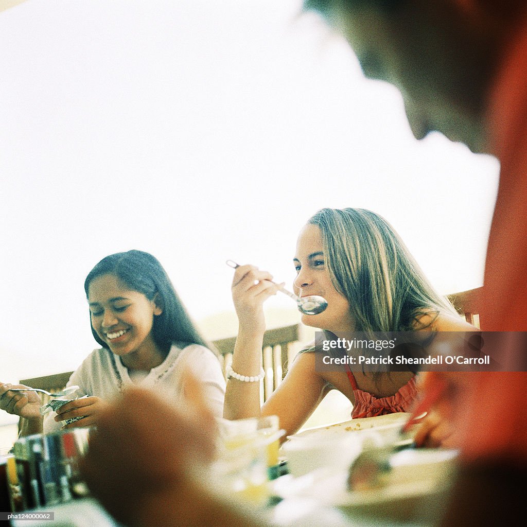 Teenage girls sitting at table, smiling