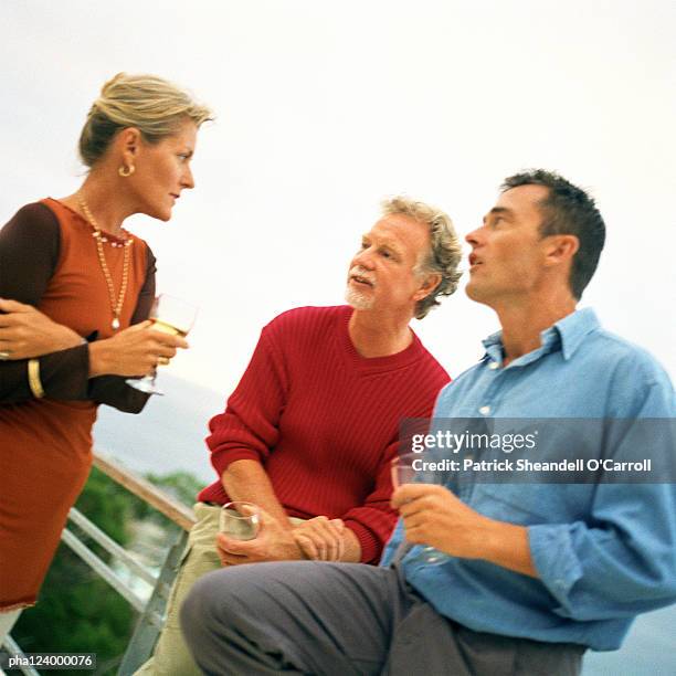 two men and woman holding glasses - balustrade stock photos et images de collection