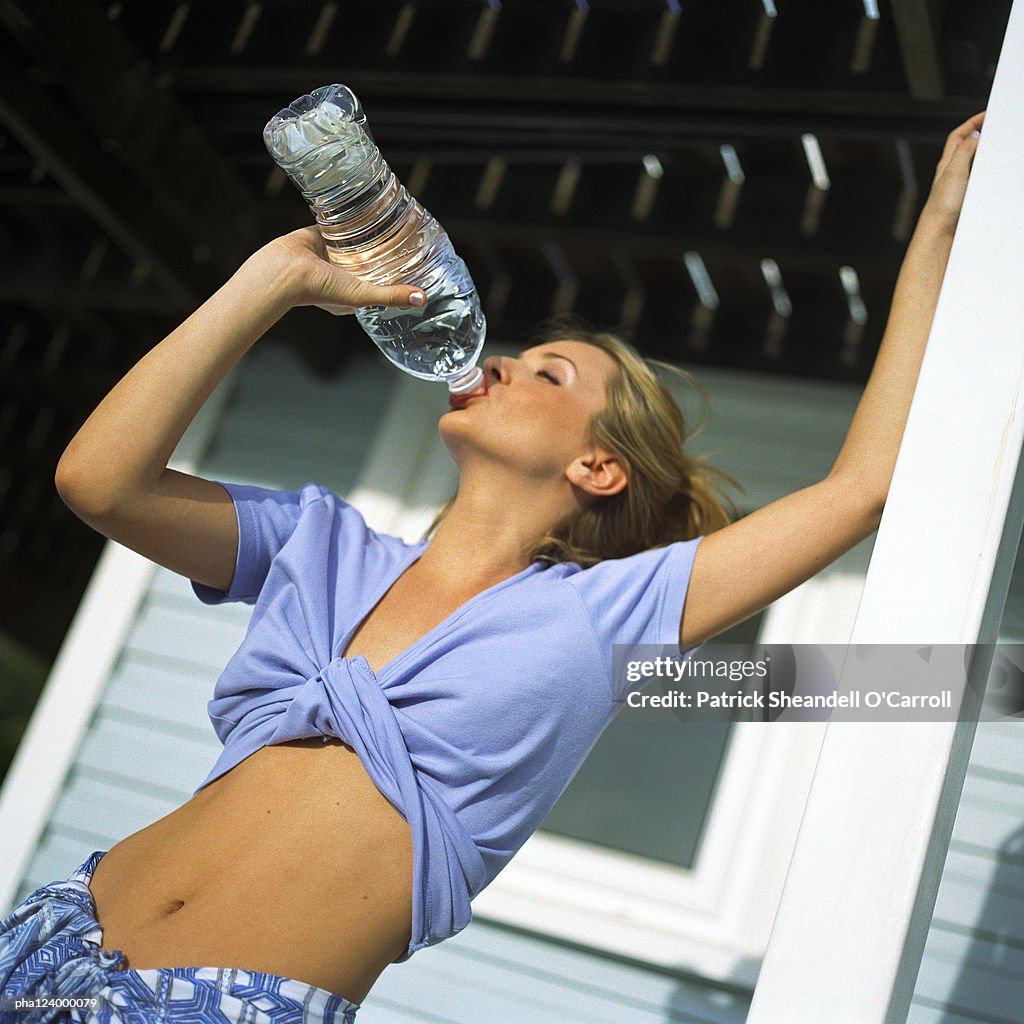 Woman drinking from plastic bottle, low angle view