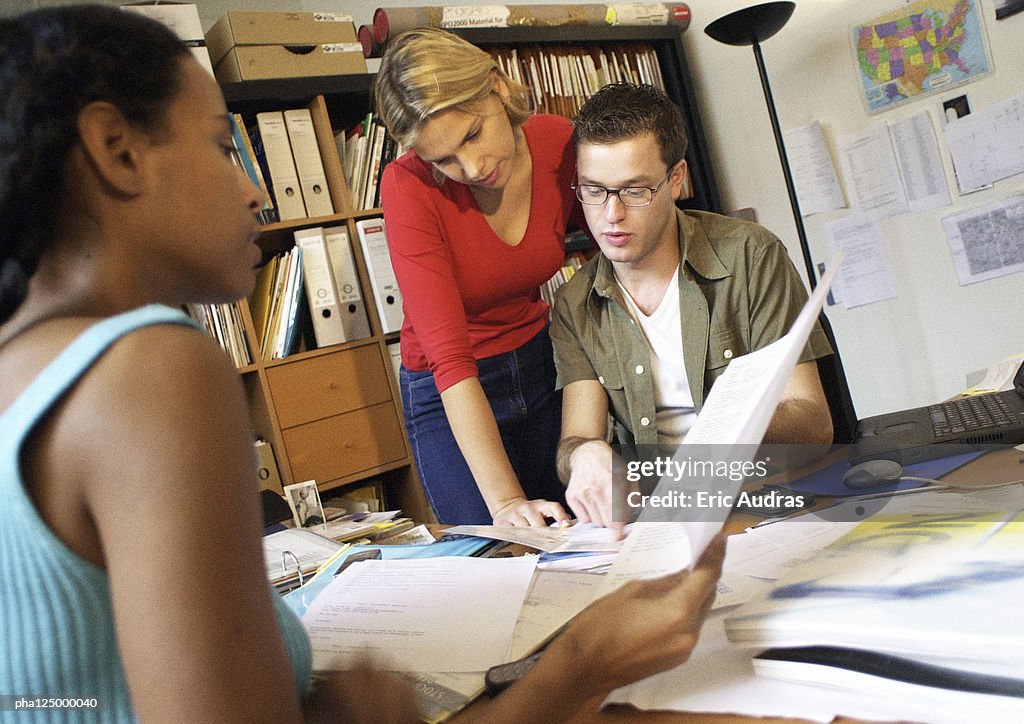 Two women and man at desk examining documents