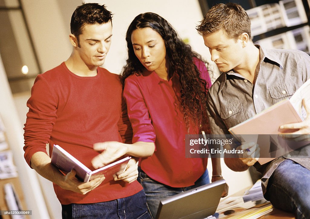 Two men and woman examining documents