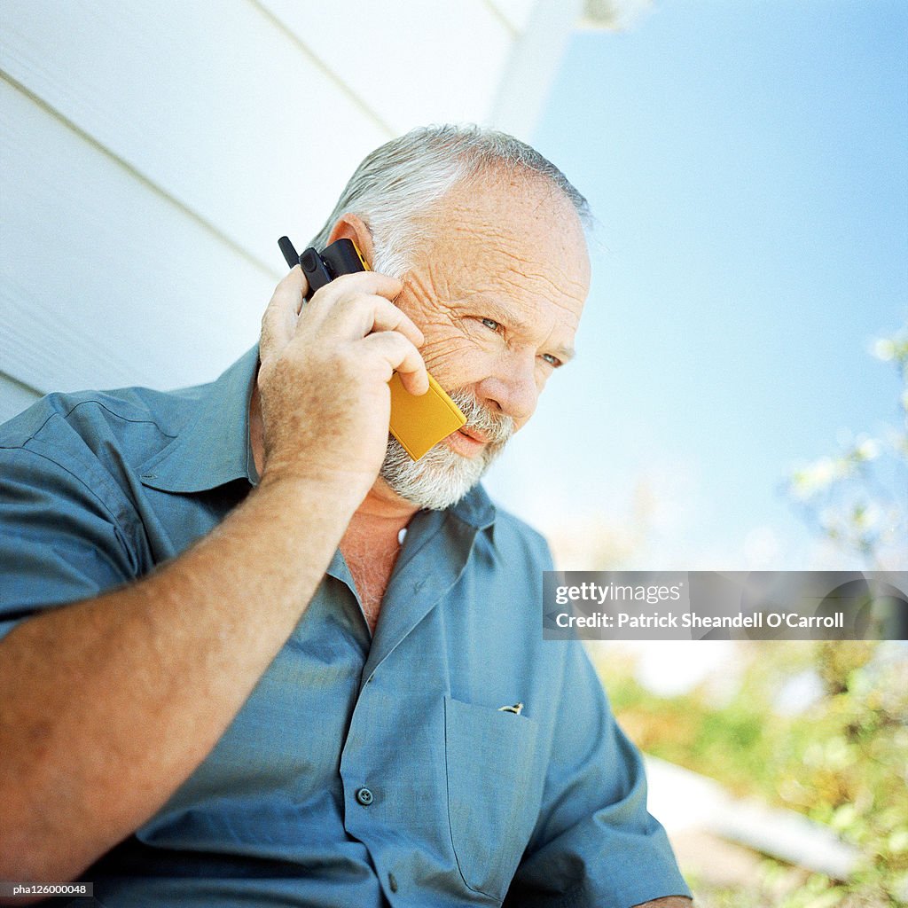 Mature man using cell phone, outside