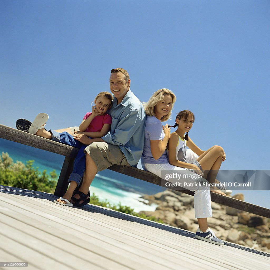 Mature couple sitting back to back with children, outside