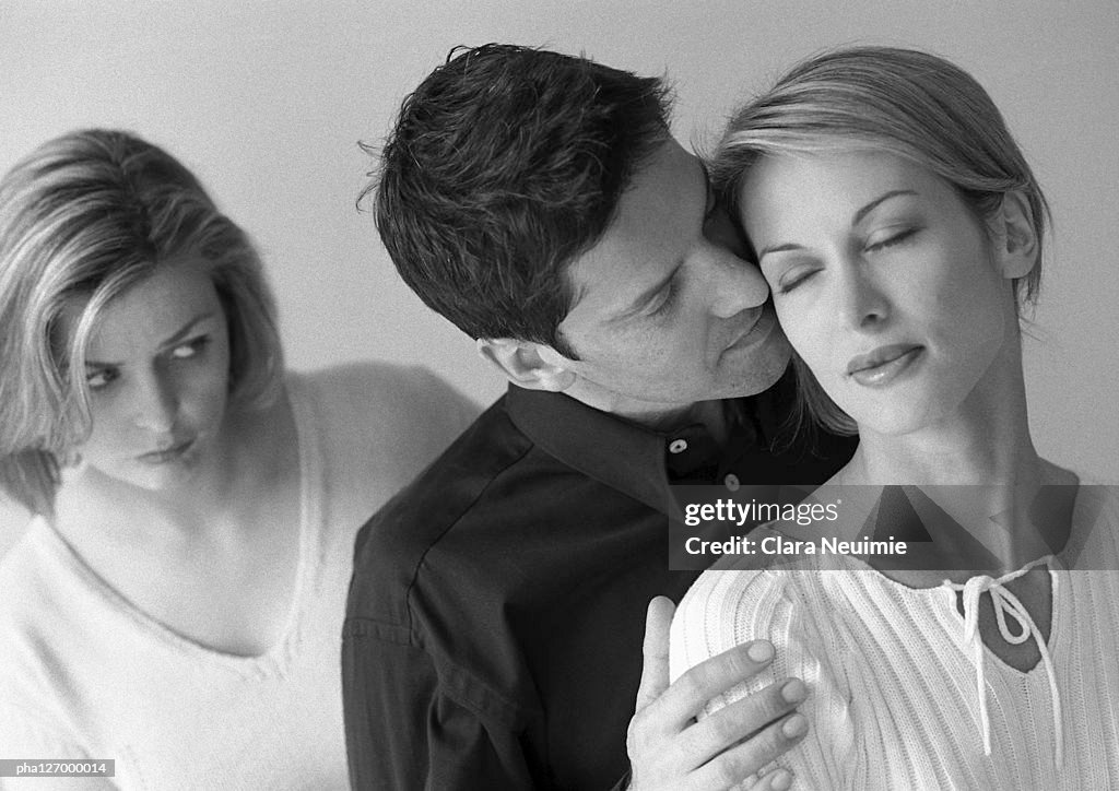 Woman standing behind couple hugging, b&w