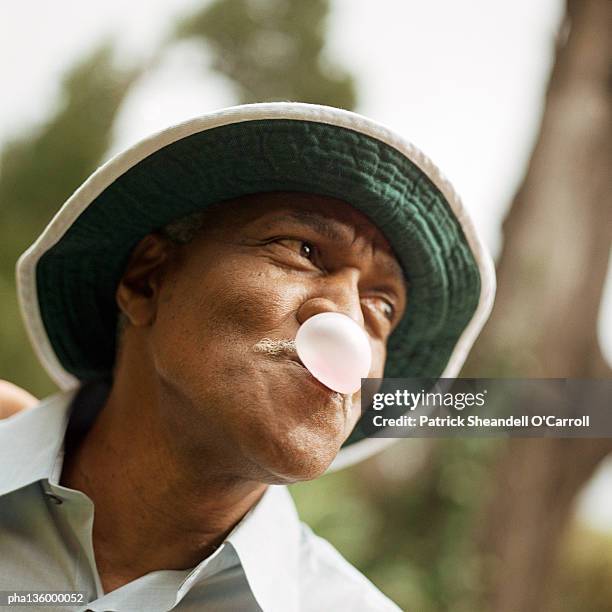 angled portrait of man blowing a bubble with chewing gum - africain stockfoto's en -beelden