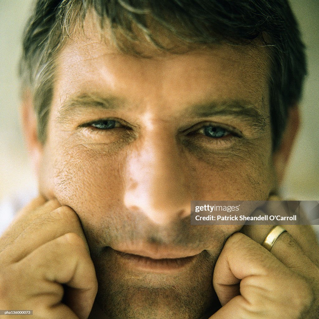 Portrait of man resting cheeks against both fists