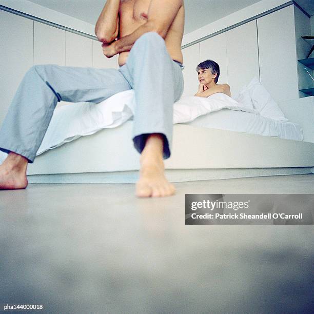 couple in bedroom, man sitting at end of bed, low angle view - world premiere of the end of longing written by and starring matthew perry stockfoto's en -beelden