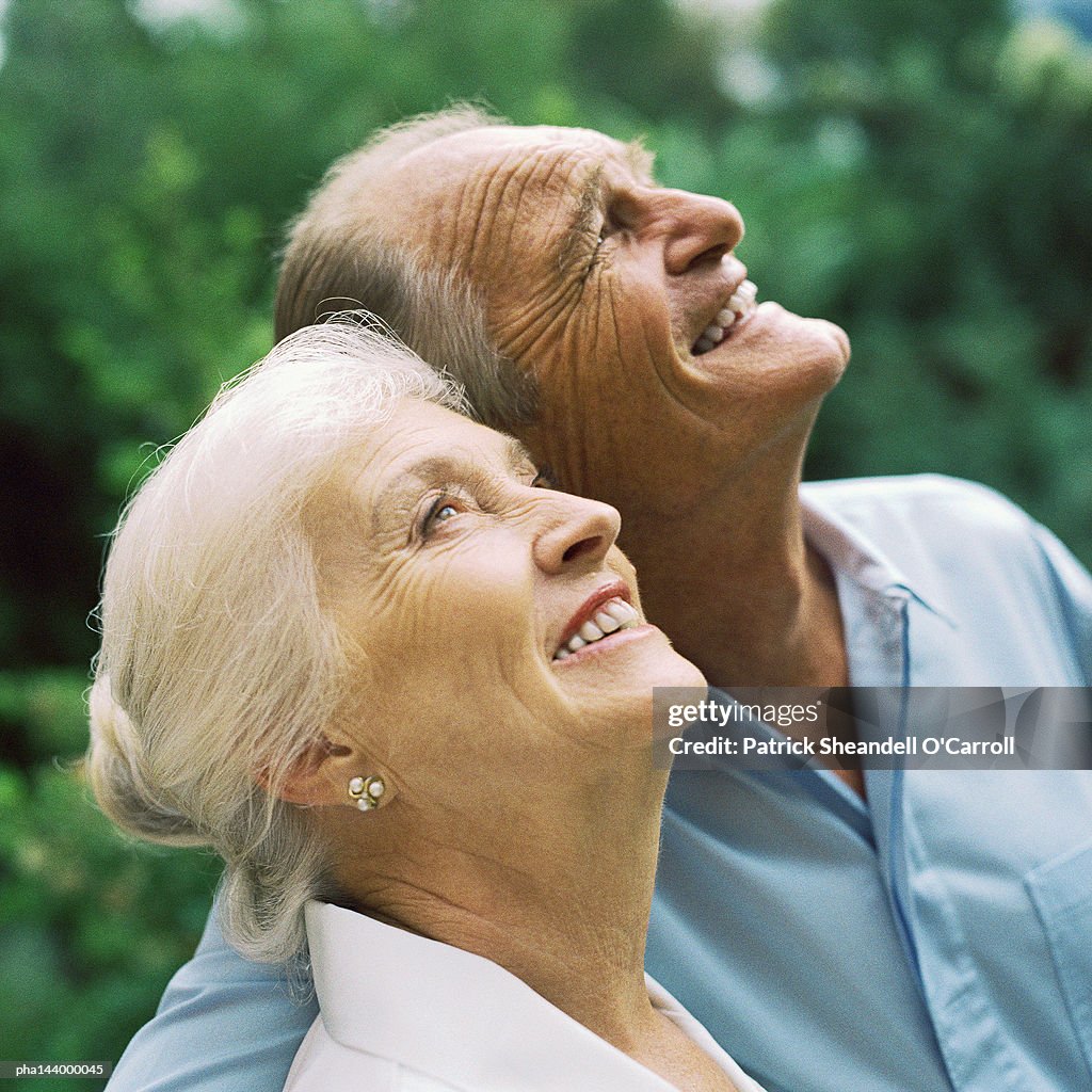 Mature couple arm in arm, looking up