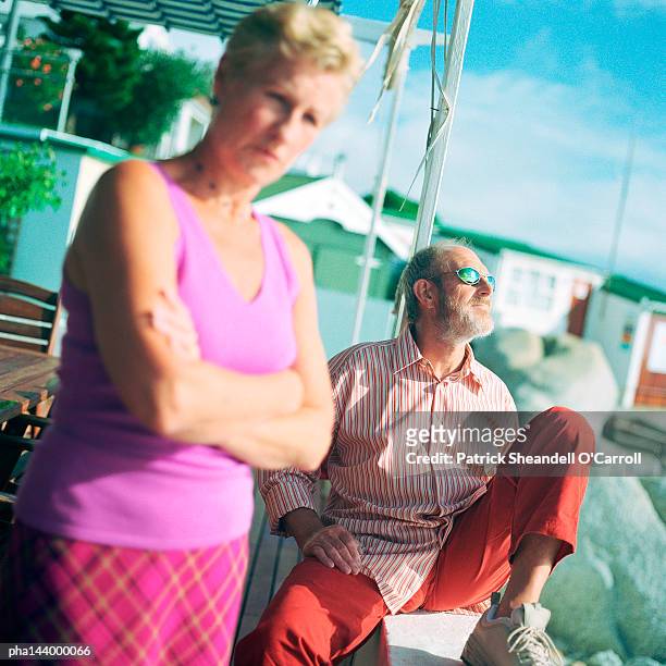 mature man and woman outside, man wearing sunglasses - grumpy old man stock-fotos und bilder