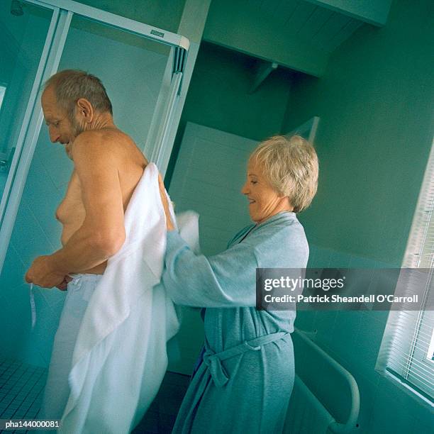 mature woman drying man's bare back, side view - bare back stock-fotos und bilder