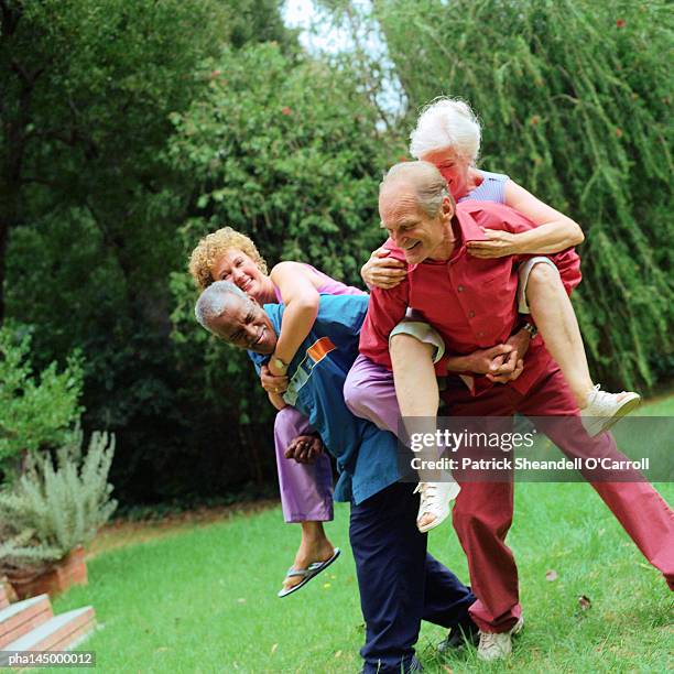 two mature men giving women piggyback rides - carroll gardens stock pictures, royalty-free photos & images