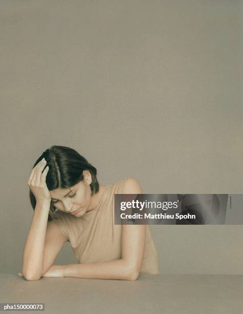 businesswoman sitting at table with hand on head, portrait - head on table stock-fotos und bilder