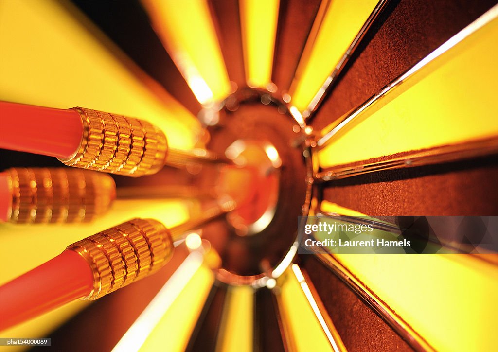 Darts in center of dartboard, close-up.