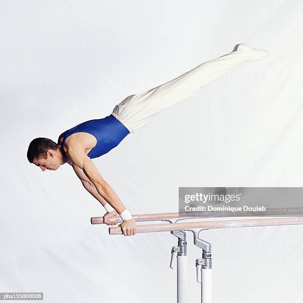 young male gymnast performing routine on parallel bars. - parallel bars gymnastics equipment stock-fotos und bilder