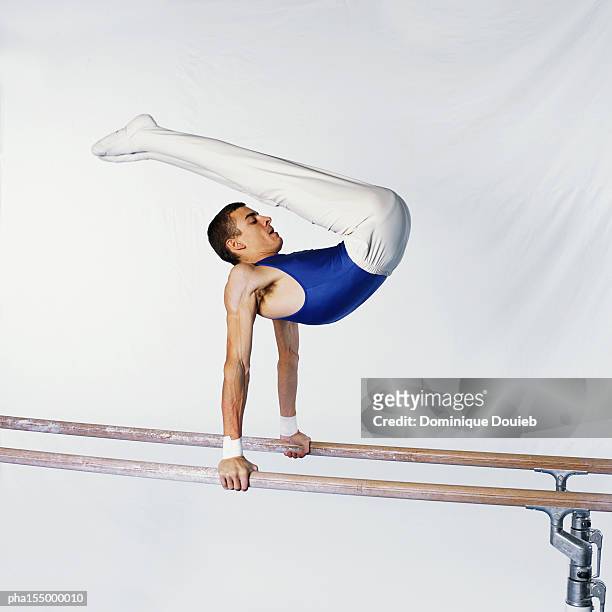 young male gymnast on parallel bars, side view. - parallel bars gymnastics equipment stock-fotos und bilder