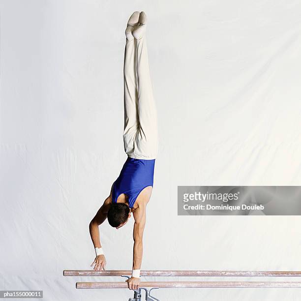 male gymnast performing routine on parallel bars, rear view. - parallel bars gymnastics equipment photos et images de collection