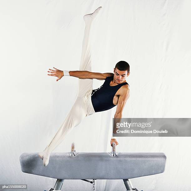 young male gymnast performing scissors routine on pommel horse. - male gymnast stockfoto's en -beelden