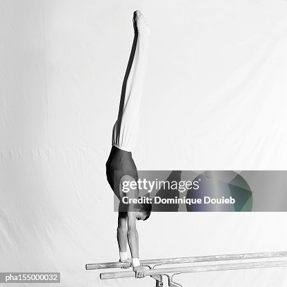 Young male gymnast upside down on parallel bars, side view. Young male gymnast upside down on parallel bars, side view.