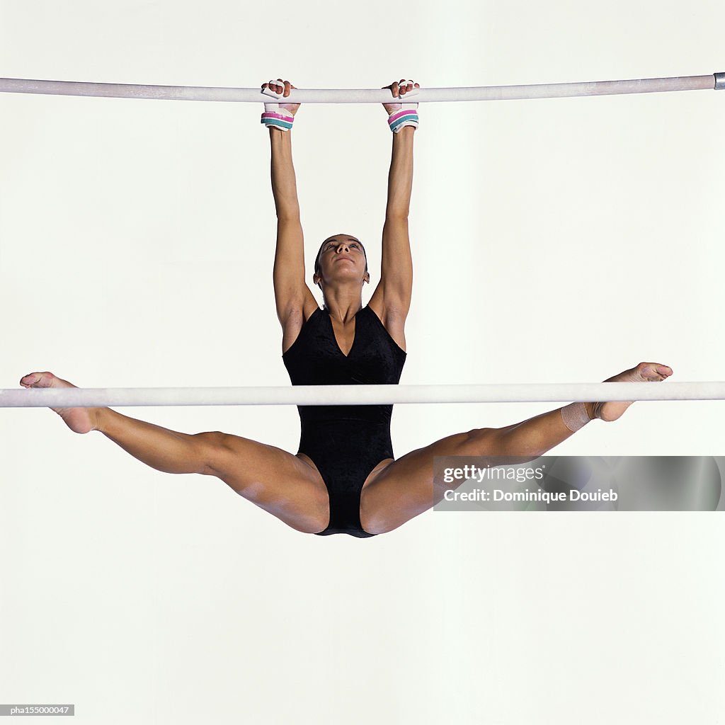 Female gymnast performing on uneven bars..