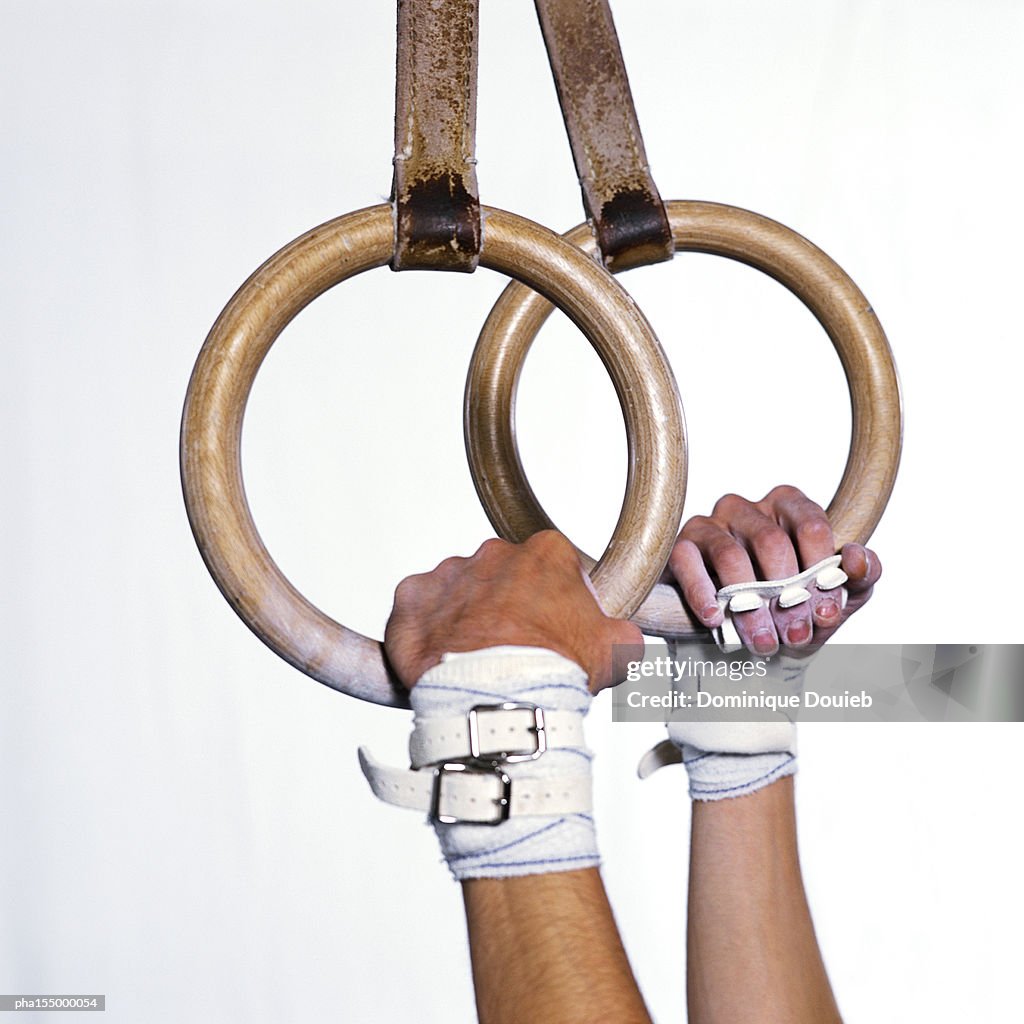 Gymnast holding rings, side view, close-up.