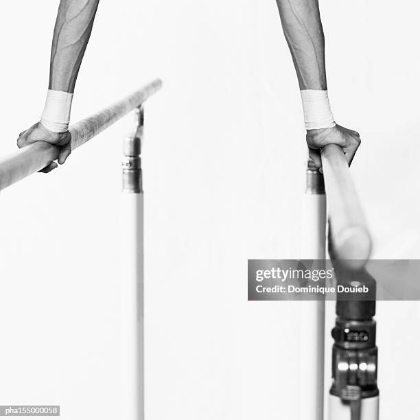 male gymnast performing handstand on parallel bars, close-up, b&w. - parallel bars gymnastics equipment stock-fotos und bilder