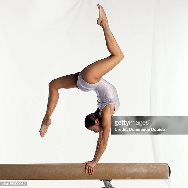 young female gymnast on balance beam performing exercise, side view. - 平均台 ストックフォトと画像