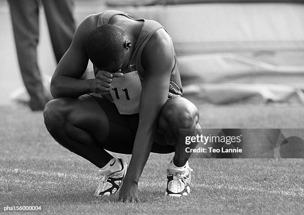 male athlete crouching, concentrating, b&w - africain stockfoto's en -beelden