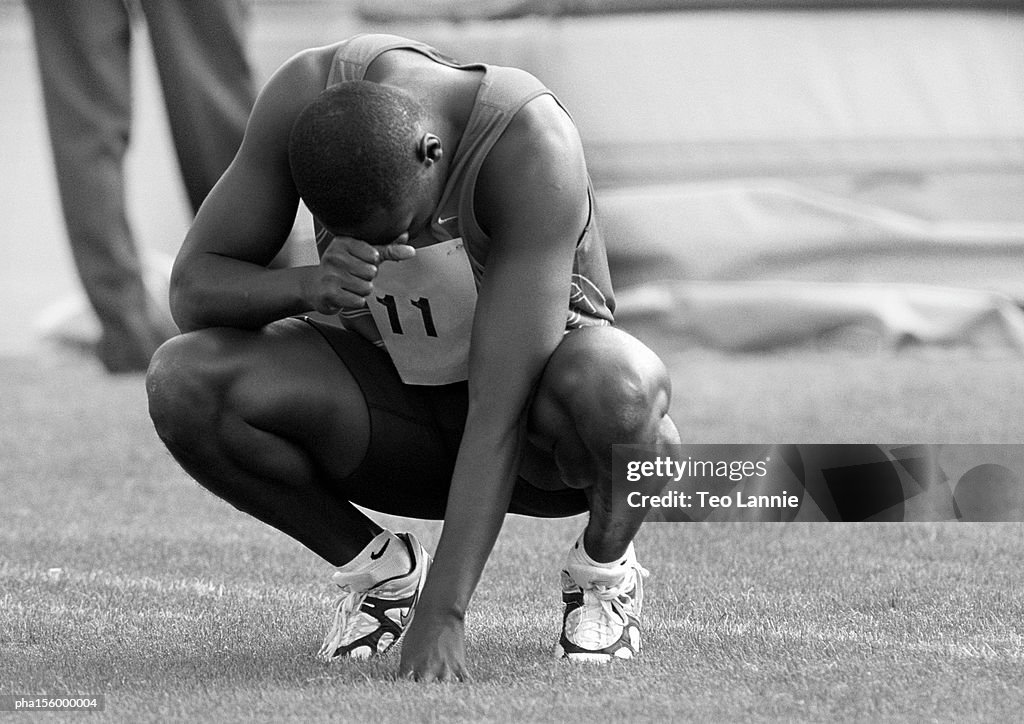 Male athlete crouching, concentrating, b&w