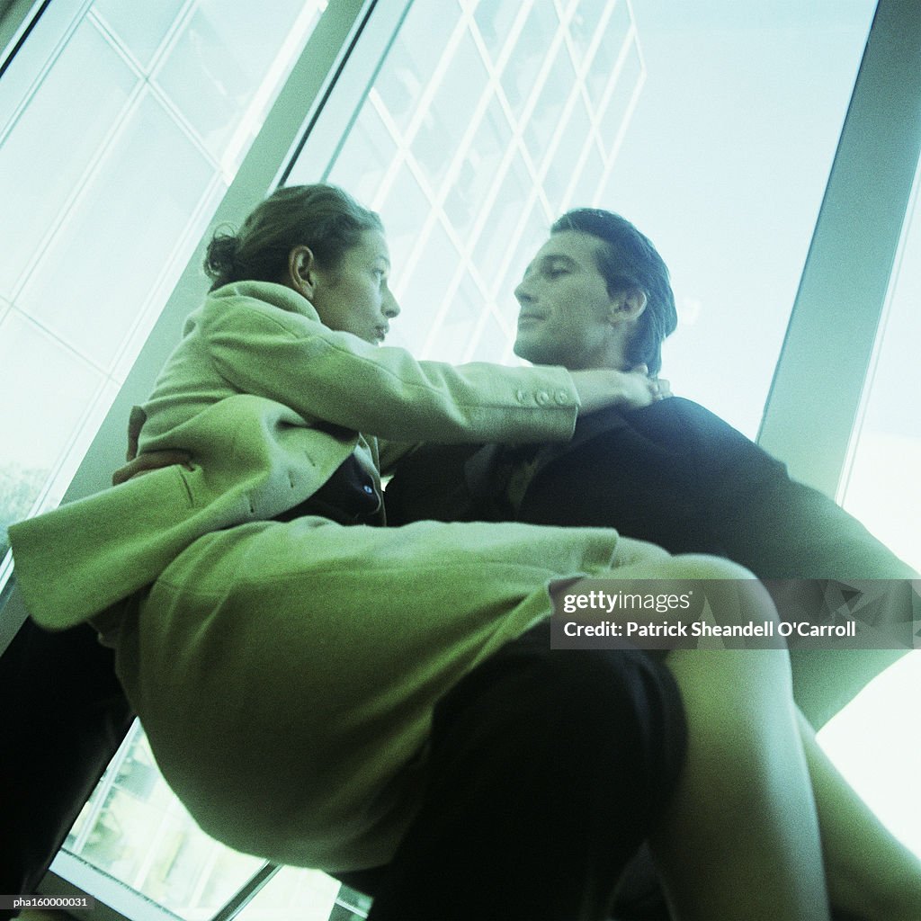 Woman sitting in man's lap, low angle view, blurred.