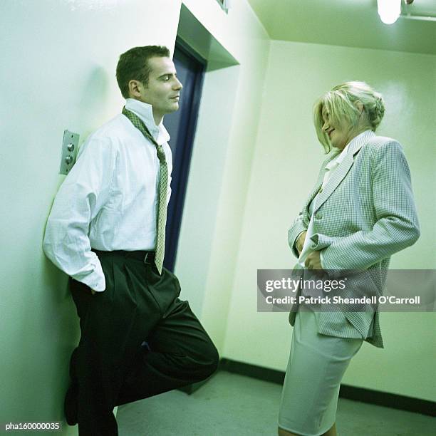 young man leaning on wall, woman adjusting her clothing, side view. - spogliarsi foto e immagini stock