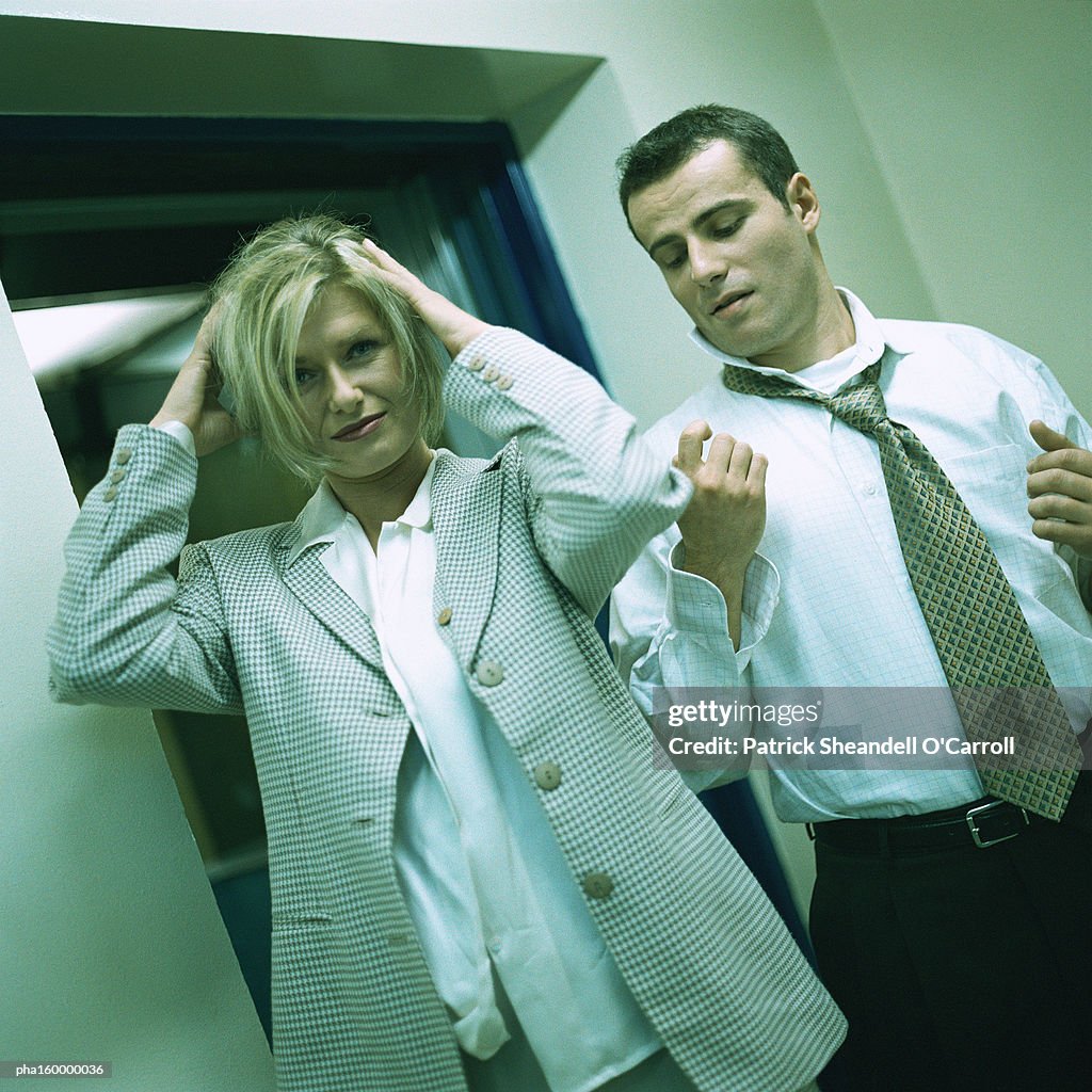 Young businessman looking at woman, woman looking into camera, portrait.