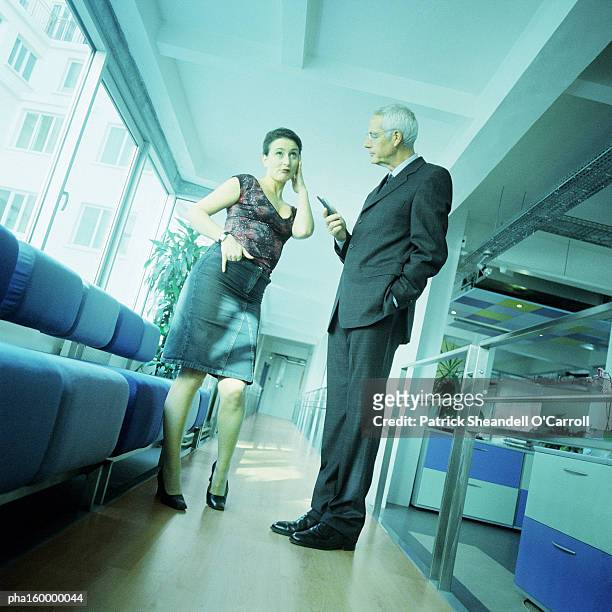 mature man in suit holding cell phone, talking to young woman. - carroll photos et images de collection