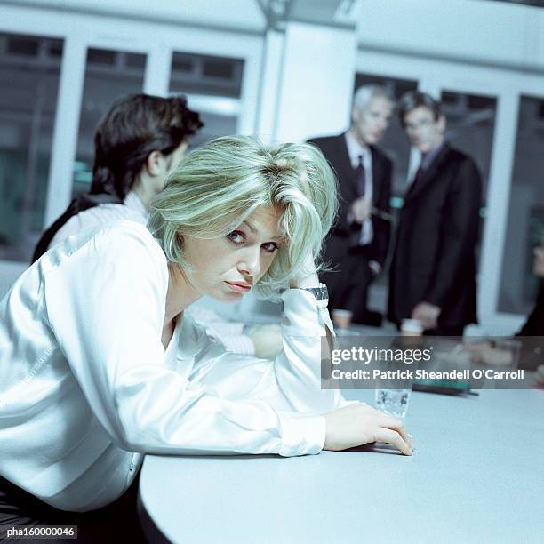 businesswoman looking into camera pouting, colleagues in background, focus on foreground. - carroll stock pictures, royalty-free photos & images