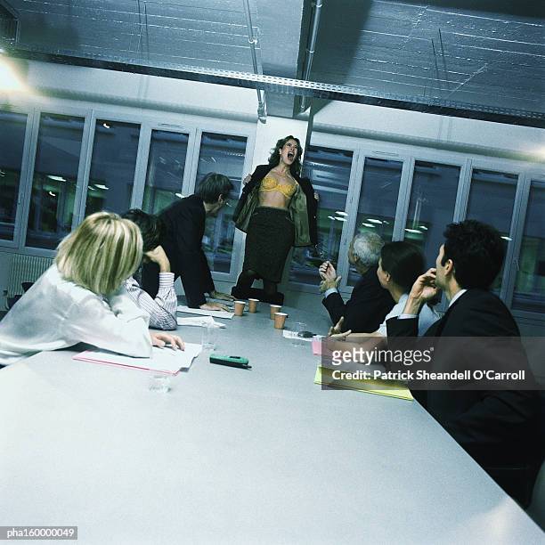 young woman office worker standing on chair, stripping, colleagues watching. - harassment man woman office stock-fotos und bilder