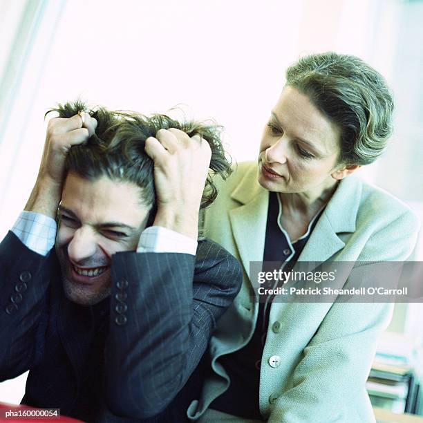 man in suit pulling his hair, woman behind watching, portrait. - o foto e immagini stock