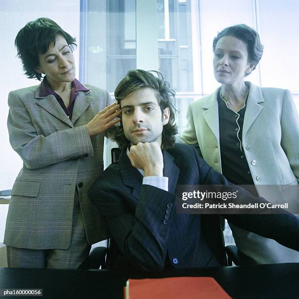 young man looking into camera, two women behind him, one touching his hair. - carroll stock pictures, royalty-free photos & images