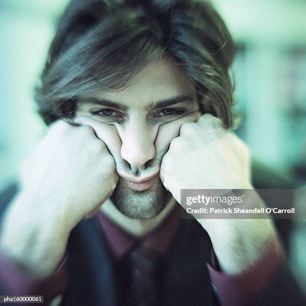 businessman looking into camera, head in hands, portrait. - o foto e immagini stock