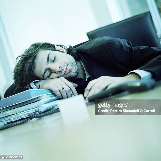 young businessman sleeping at desk. - o foto e immagini stock
