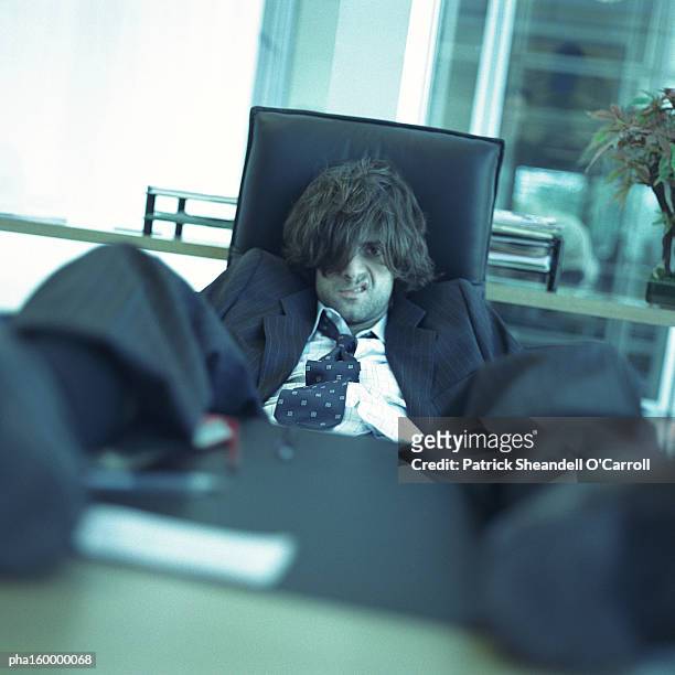 young disheveled man sitting with feet on table. - o foto e immagini stock