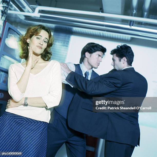 young woman looking into camera, two men in suits face to face. - o foto e immagini stock