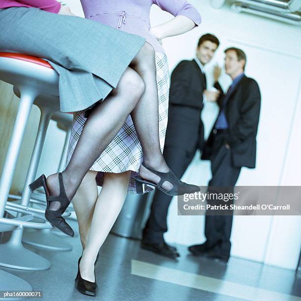 two women chatting, two men in background, focus on women's legs. - o foto e immagini stock