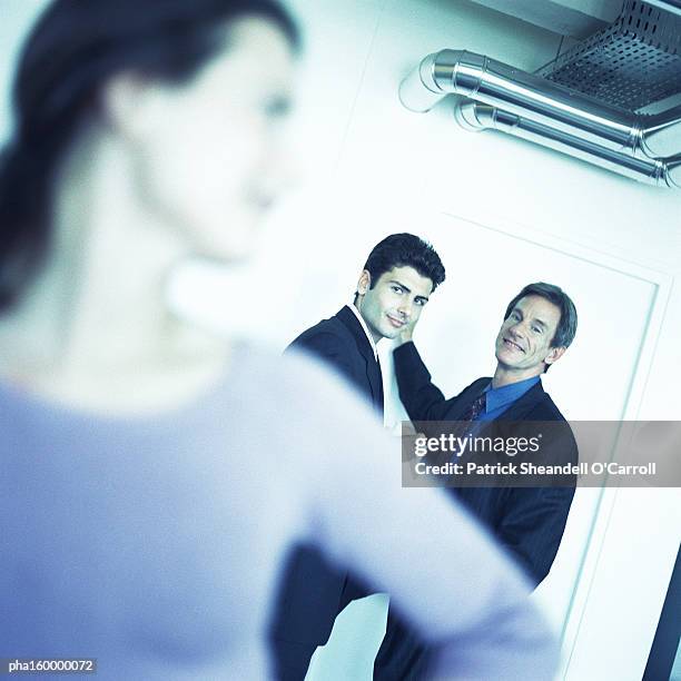 woman standing, two men in background, focus on background. - carroll stock pictures, royalty-free photos & images