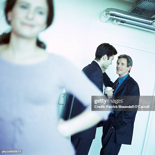 woman standing, two men in background, focus on background. - carroll stock pictures, royalty-free photos & images