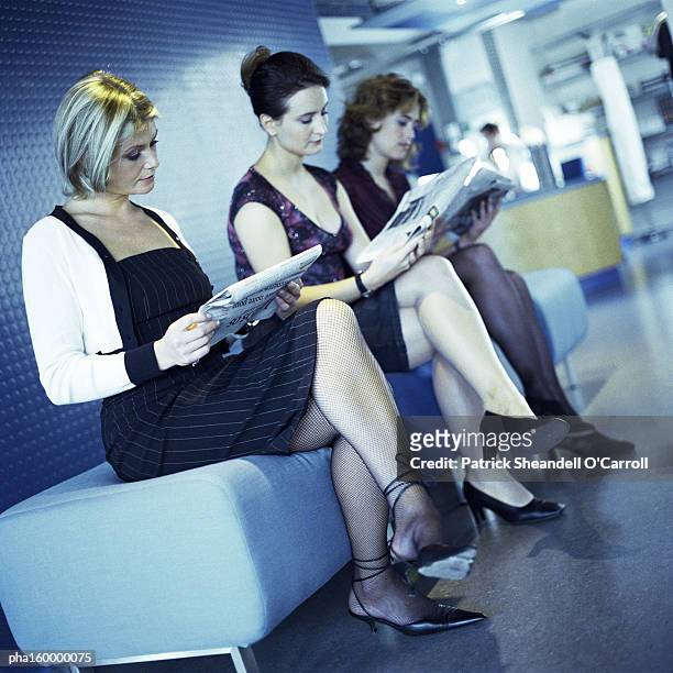 three young women sitting, reading, side view. - o foto e immagini stock