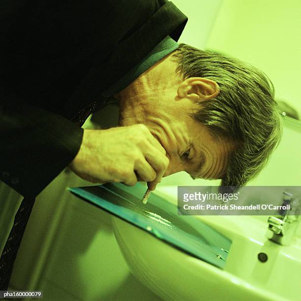 man in suit snorting cocaine in bathroom. - carroll stock pictures, royalty-free photos & images