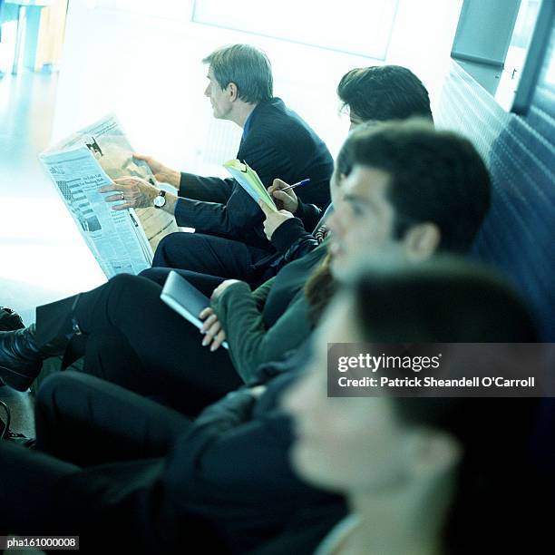 men and women sitting together on bench, side view. - o foto e immagini stock