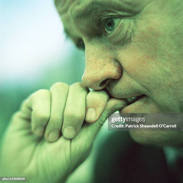 extreme close-up of man biting thumb, side view, cool tone. - o foto e immagini stock