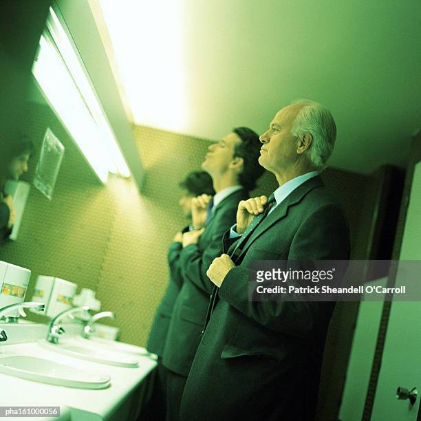 businessmen in bathroom fixing ties. - carroll photos et images de collection