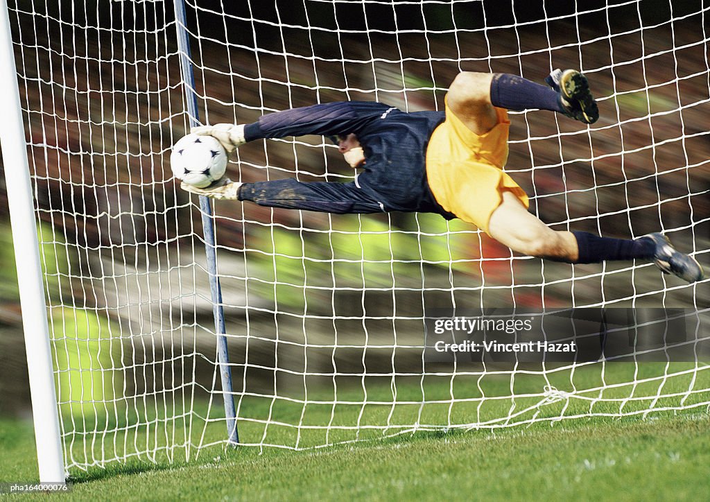 Goal keeper, horizontal, saving ball during match, full length